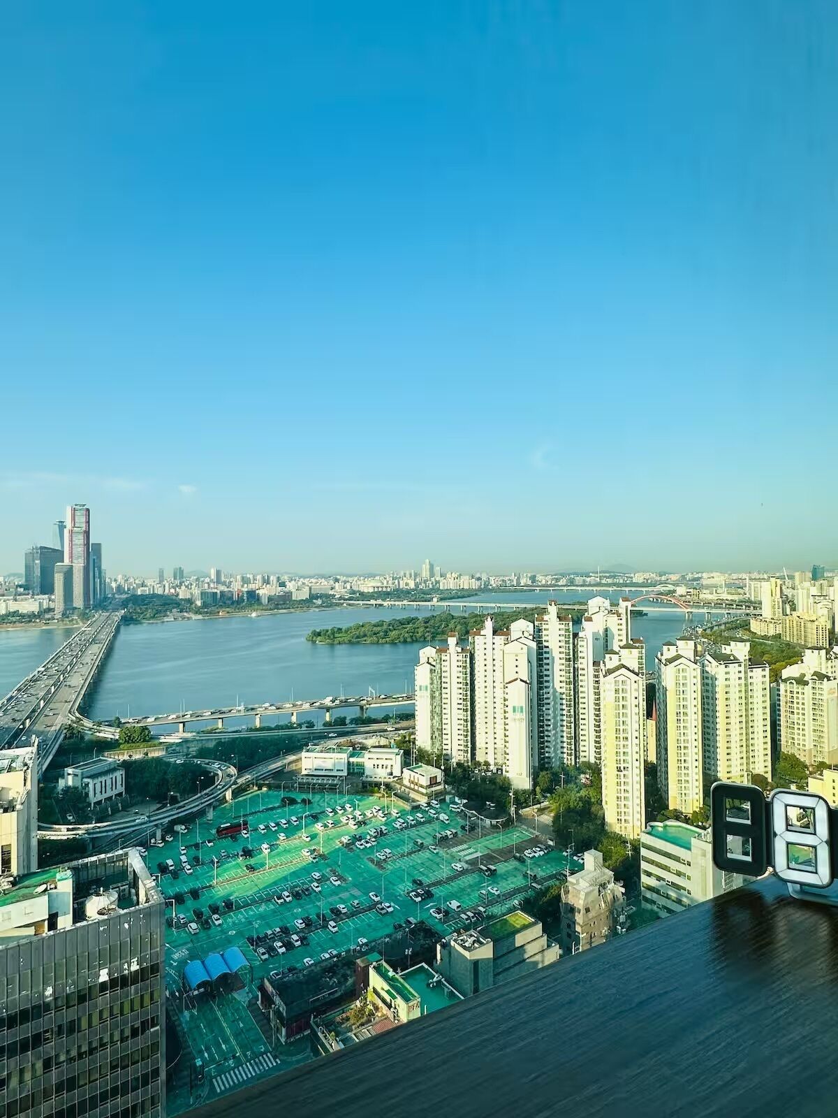 A high-rise building with a view of a river and a bridge in the background.