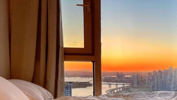 Une chambre avec une grande fenêtre, un lit et des rideaux.
