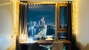 Une pièce avec un bureau, deux chaises, un ordinateur portable et une vue sur le paysage urbain illuminé la nuit.