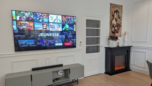 Una sala de estar con un televisor de pantalla plana montado en la pared que muestra diversos carteles de películas.