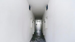 Un pasillo largo y estrecho con paredes blancas y suelo de hormigón.