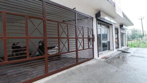 Un edificio con una reja metálica cerrada y un automóvil estacionado en el interior.