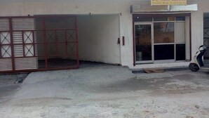 Un edificio con entrada protegida por una reja, un cartel anunciando habitaciones y habitaciones familiares, y una moto estacionada afuera.
