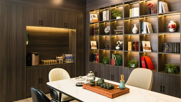 Un espace repas moderne avec une table en marbre, des chaises et un plateau en bois sur lequel sont posées des théières.