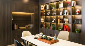 Un espace repas moderne avec une table en marbre, des chaises et un plateau en bois sur lequel sont posées des théières.