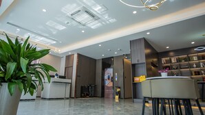 Un hall d’hôtel moderne comprenant un comptoir d’accueil, un espace salon et un mur avec des étagères.