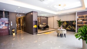 Un hall d’hôtel moderne comprenant un espace repas, un comptoir d’accueil et une bibliothèque agrémentée d’objets décoratifs.