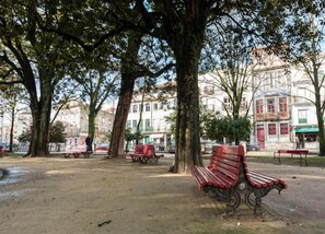 Un parc avec des bancs et des arbres, entouré d’immeubles.