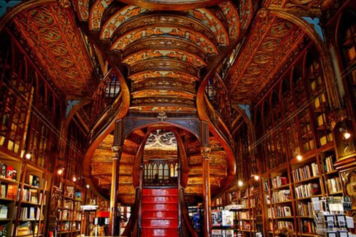 An ornate library interior with bookshelves, a central staircase, and intricate ceiling designs.