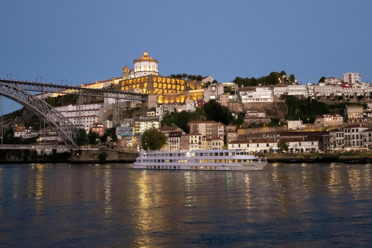Un río con un puente y un edificio grande iluminado al fondo.