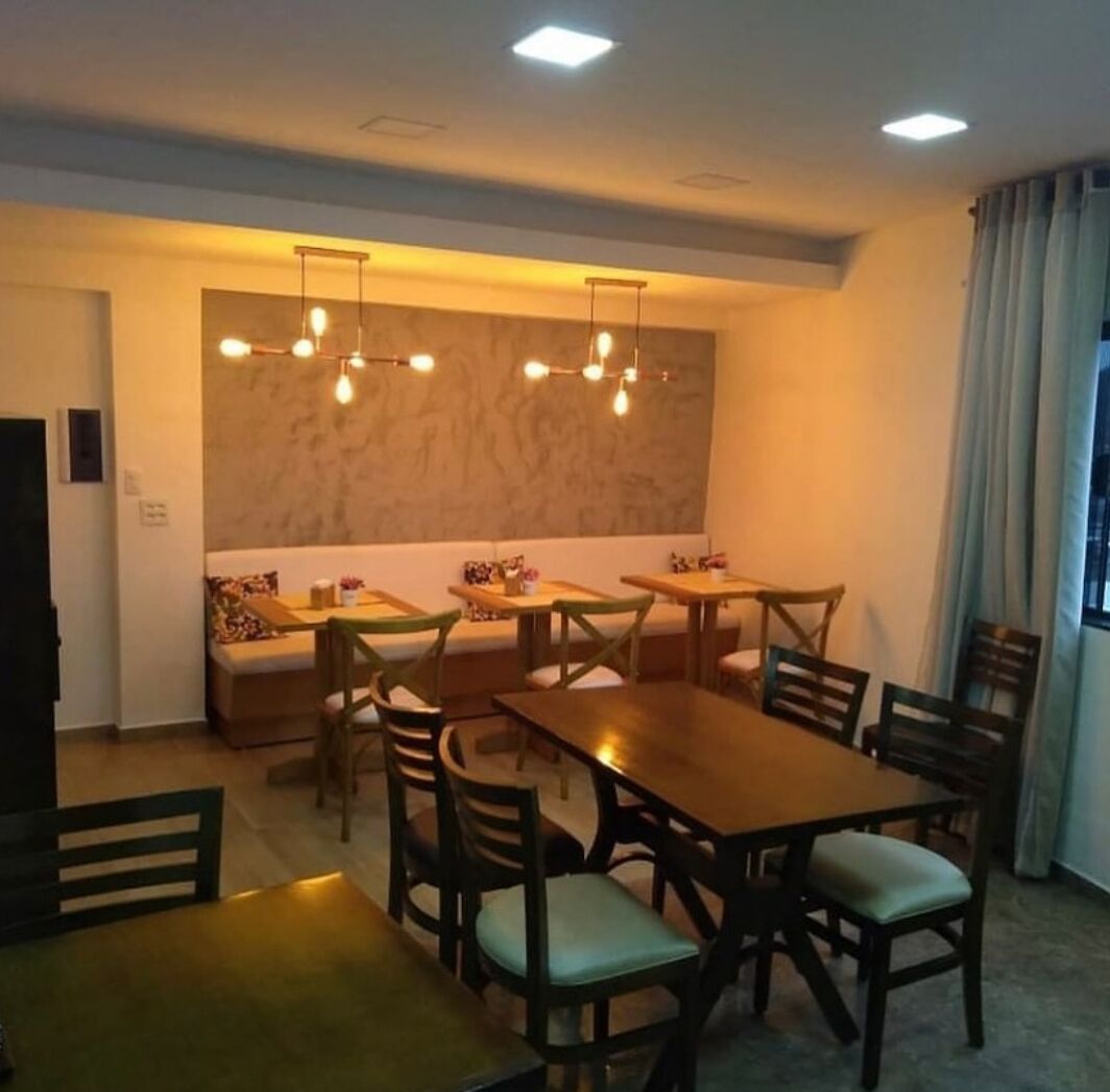 A dining area with wooden tables and chairs, a sofa, and pendant lighting.