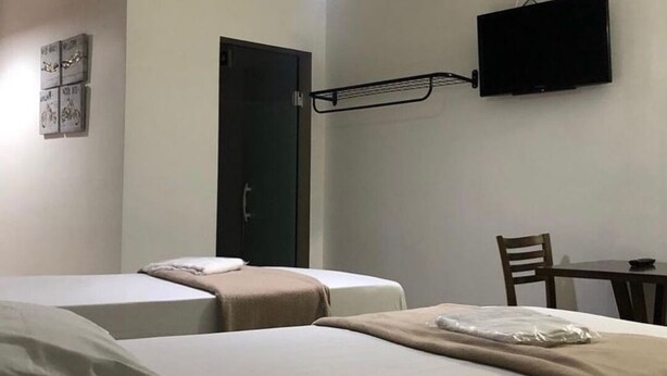 A hotel room with two beds, a TV mounted on the wall, and a door. - HOTEL GUARULHOS  (Guarulhos)