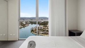 Une chambre d’hôtel dotée d’une grande fenêtre donnant sur une rivière et sur le paysage urbain.
