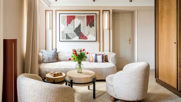A modern living room with a sofa, two armchairs, a coffee table, and a decorative vase. - Merveil Luxury Suites - Bourse I-II (Paris)