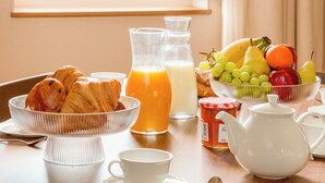 A breakfast table with croissants, juice, milk, and a fruit bowl. - Merveil Luxury Suites - Bourse I-II (Paris)