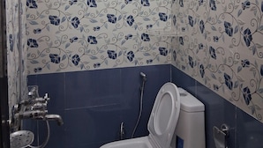 Et badeværelse med toilet, bruser og vandvarmervand.