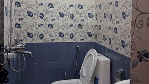 Et badeværelse med toilet, bruser og håndvask.