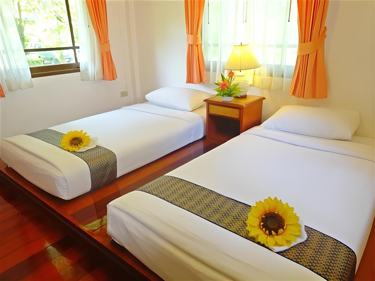 A hotel room with two single beds, a nightstand with a lamp, and a window with curtains.