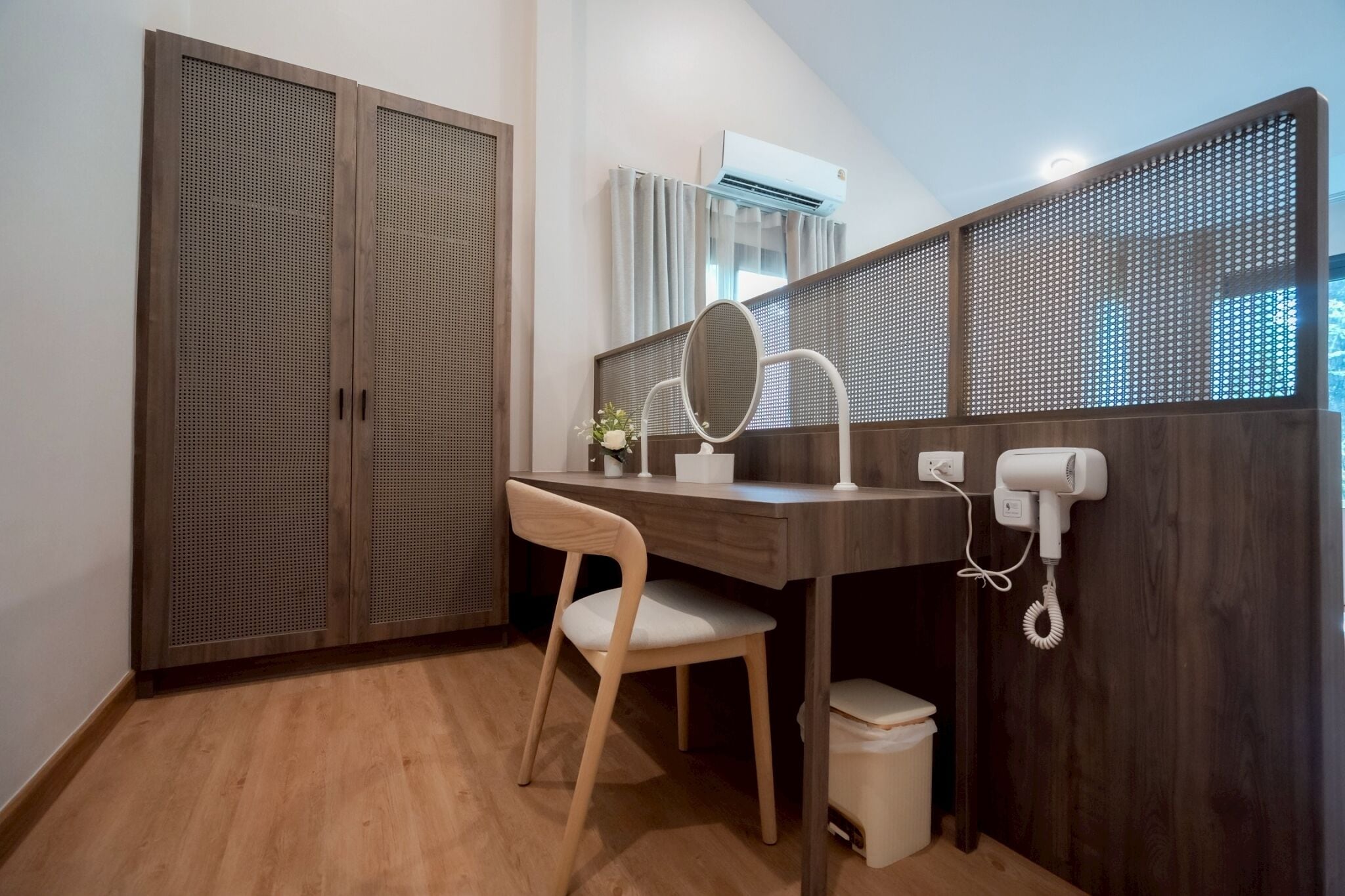 A bathroom with a wooden vanity, a mirror, a hairdryer, and a toilet.