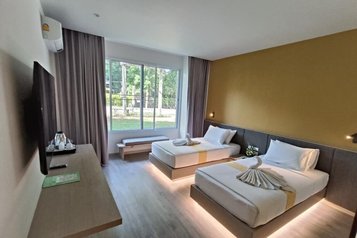 Habitación de hotel con dos camas, un escritorio, un televisor de pantalla plana y un ventanal con cortinas.