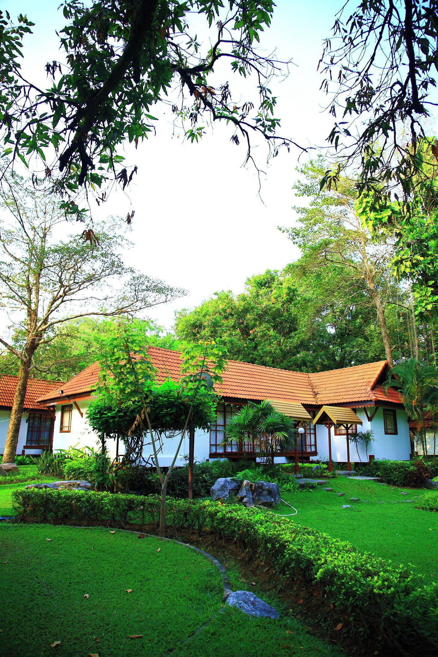 A traditional building with a tiled roof, surrounded by lush greenery and trees.