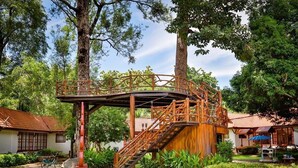A wooden bridge connecting two buildings in a lush garden setting. - Supalai Pasak Resort Hotel and Spa (Tha Khlo)