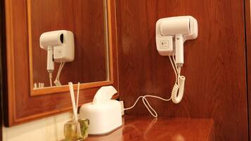 A hair dryer and a tissue box on a wooden counter in a bathroom.