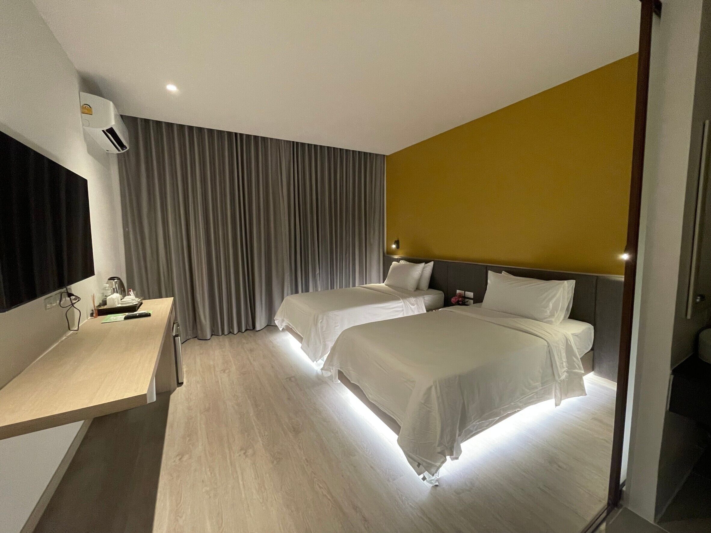 Une chambre d’hôtel avec deux lits, un bureau et une grande fenêtre avec des rideaux.