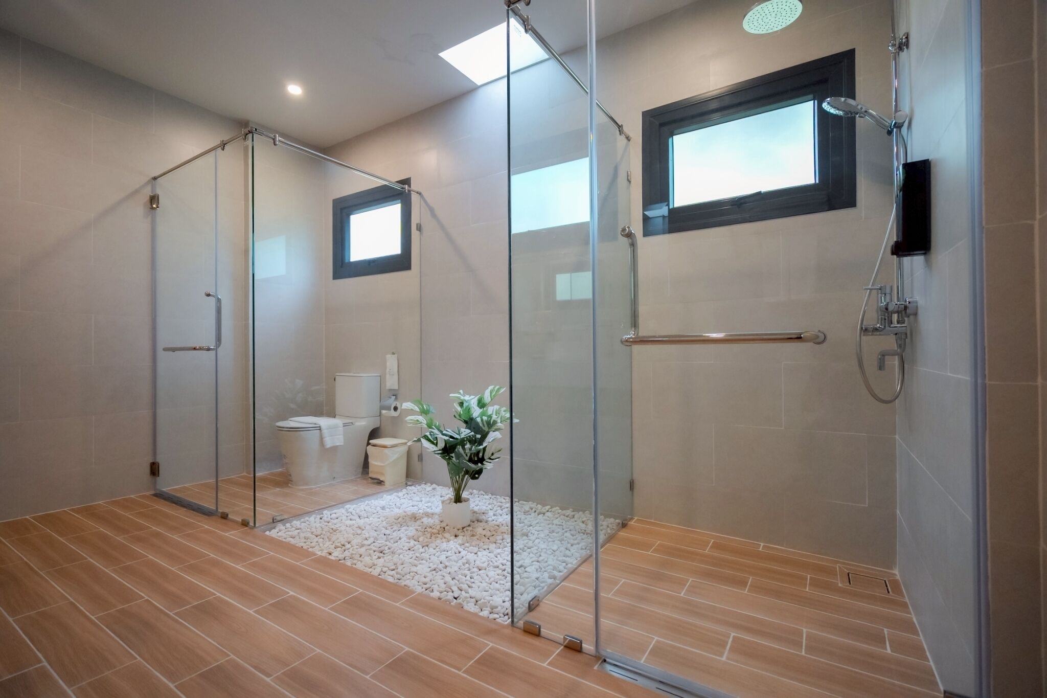 Un baño moderno con cabina de ducha de vidrio, inodoro, bidé y una planta en maceta.