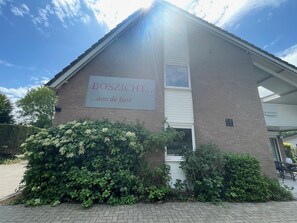 A building with a sign reading "BOSZICHT... aan de kust" and a brick exterior. - Boszicht 5 by Interhome (Oostkapelle)