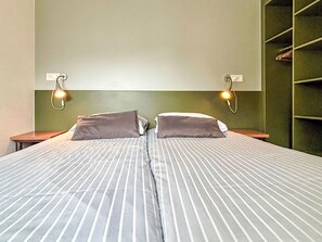 A double bed with striped bedding, two bedside tables, wall-mounted reading lights, and a green wall. - Boszicht 5 by Interhome (Oostkapelle)