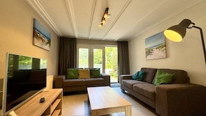 A living room with a TV, two sofas, a coffee table, and a lamp.