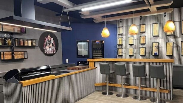 Ein moderner Küchenbereich mit einer Bar, Barhocker und einem Logo an der Wand.