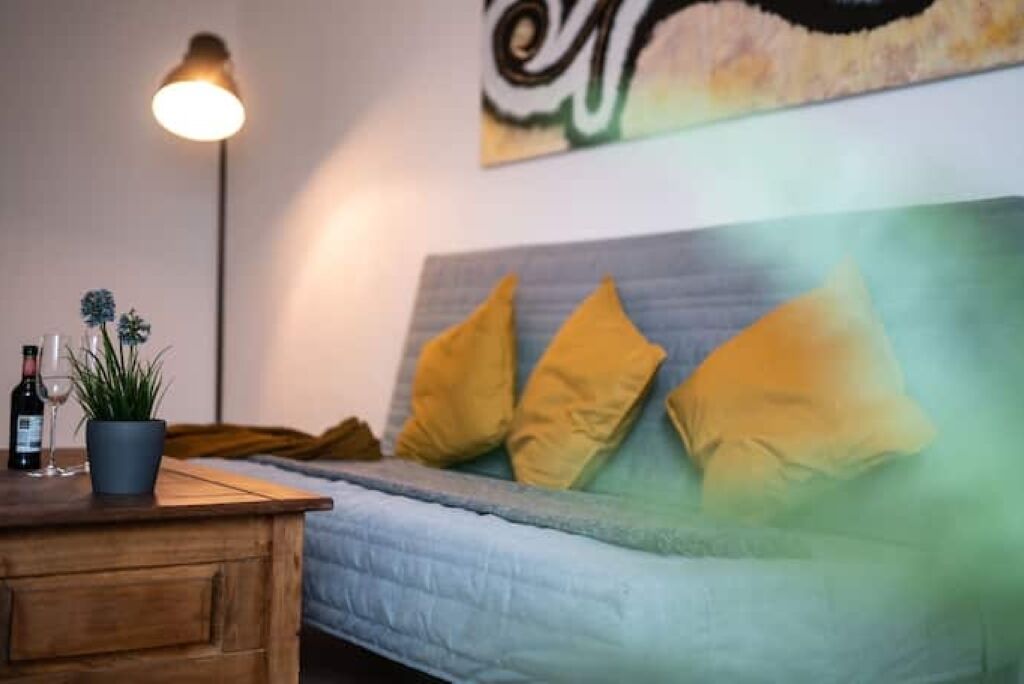 A room with a bed, a bedside table with a lamp, and a wall with a painting.