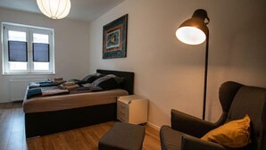 Un dormitorio con cama, mesita de noche, silla y lámpara de pie.