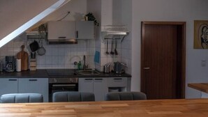A modern kitchen with a wooden dining table, grey cabinets, and a built-in oven.