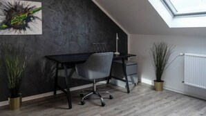 A modern office space with a desk, chair, and potted plants.