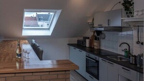A compact kitchen with a skylight, a wooden counter, and a view of the outside.