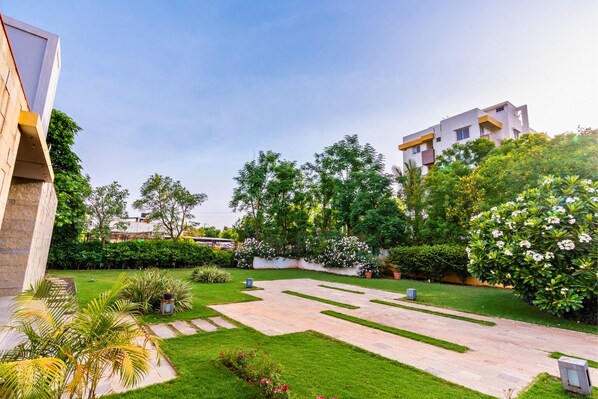 A modern building with a courtyard featuring a well-maintained lawn, stone pathways, and various plants.