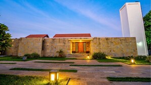 A modern building with a stone facade, a red-tiled roof, and a well-lit entrance. - Cherry Villa,Nashik by Ebony Stays | Cosy 4BHK Villa in Nashik with Scenic Views (Nashik)