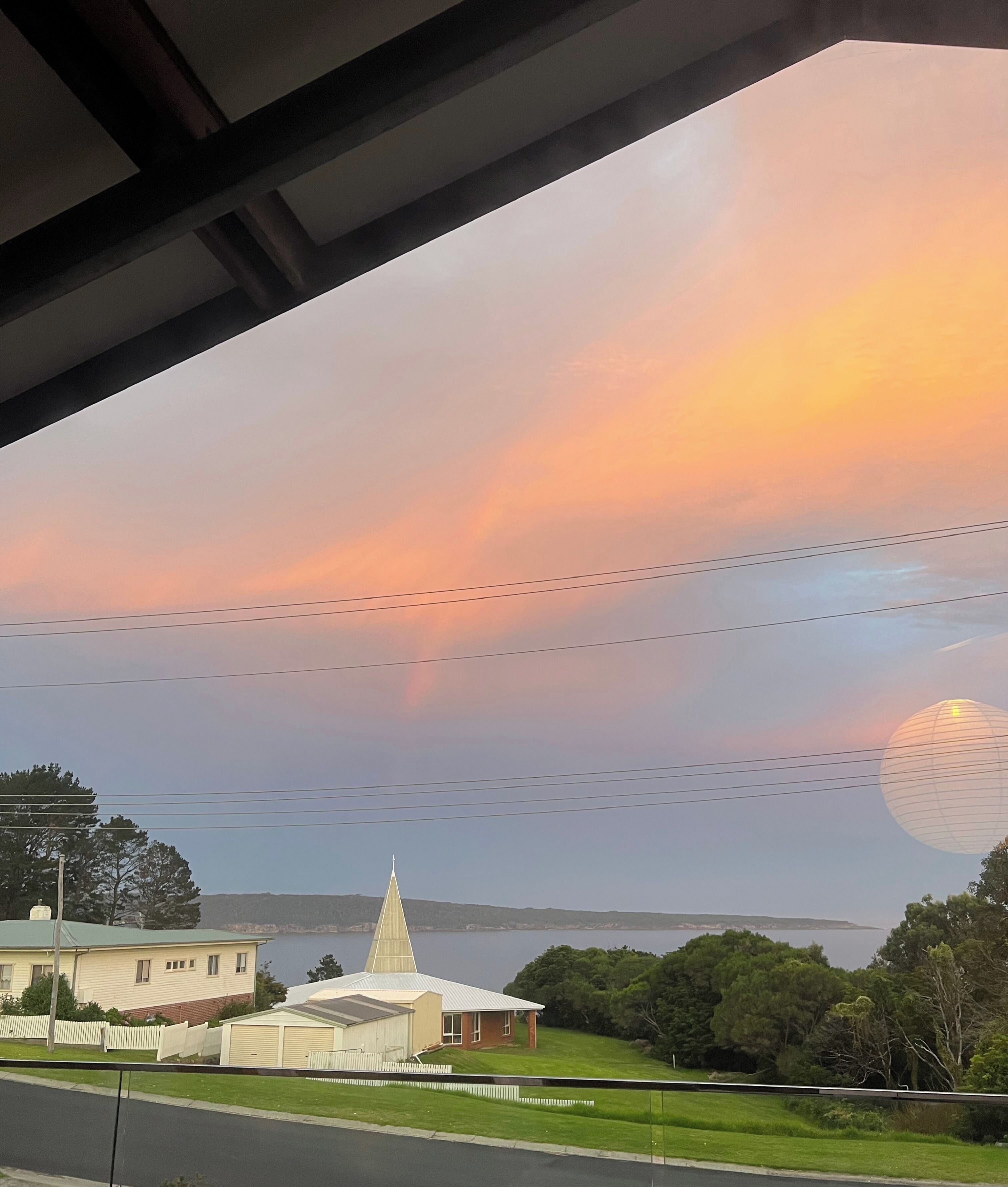 A view of a church with a steeple, a body of water, and a clear sky.