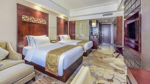 A hotel room with two beds, a sofa, a TV, and a decorative wall.