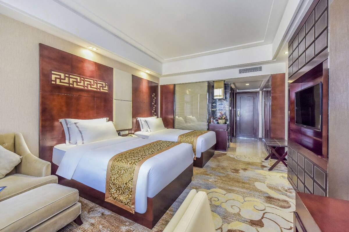Une chambre d’hôtel avec deux lits, un canapé, une télévision et un mur décoratif.