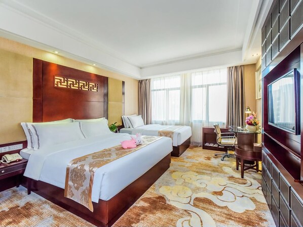 A hotel room with two beds, a desk, a chair, a TV, and a large window with curtains.