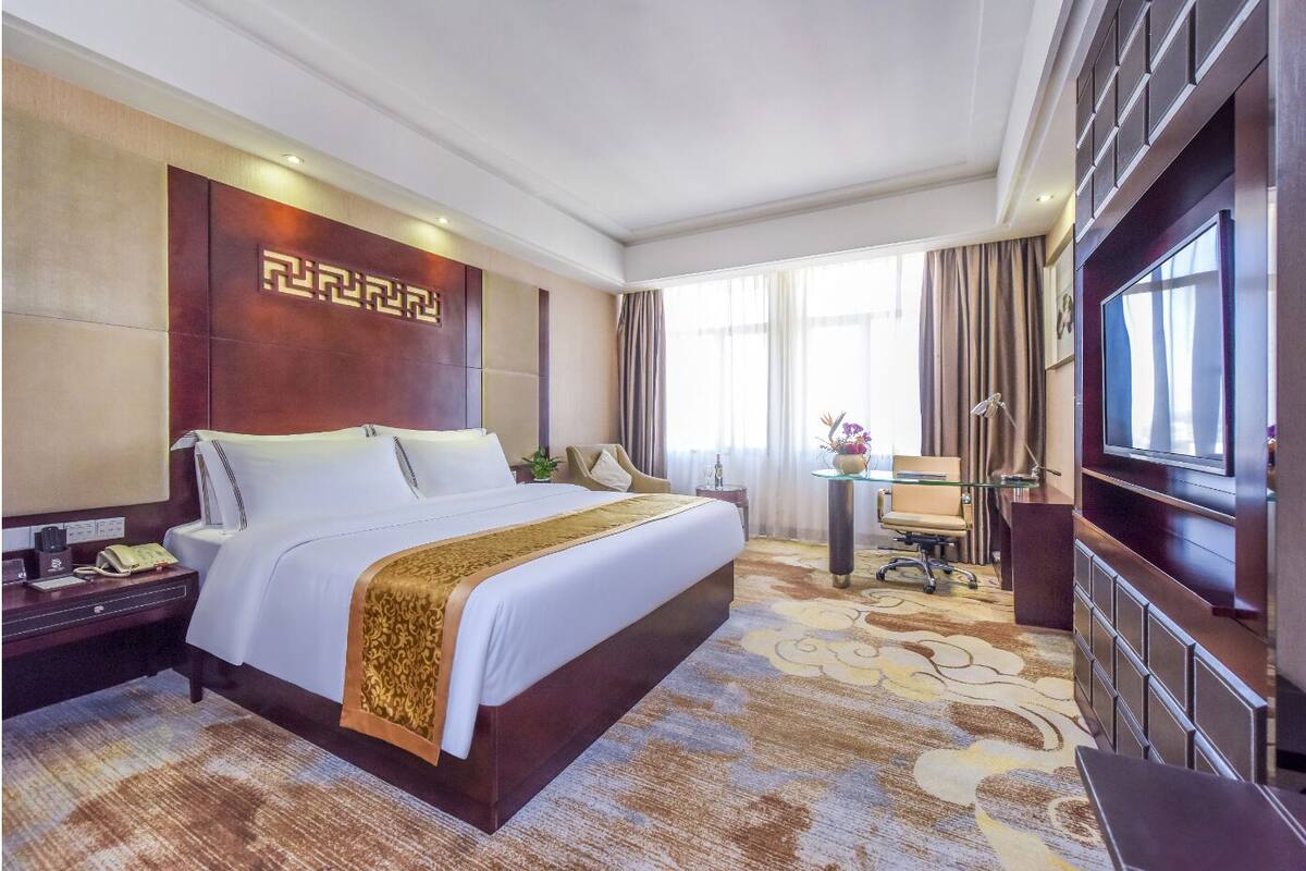 Une chambre d’hôtel avec un grand lit, un bureau, une télévision et un minibar.