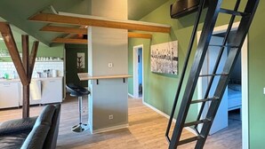 Ein Loft-Zimmer mit Küchenzeile, Esstisch und einer Treppe.
