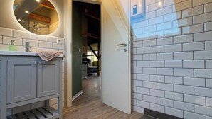 Ein modernes Badezimmer mit einem runden Spiegel, grauen Schränken und einem Holzboden.