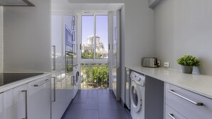 A modern kitchen with a view of a building through a glass door. - Corcovada Sunset (Albufeira)
