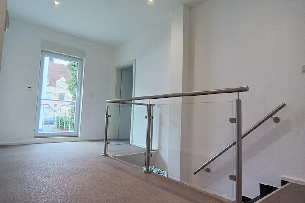 A spacious room with a glass railing, a large window, and a door leading to another room.