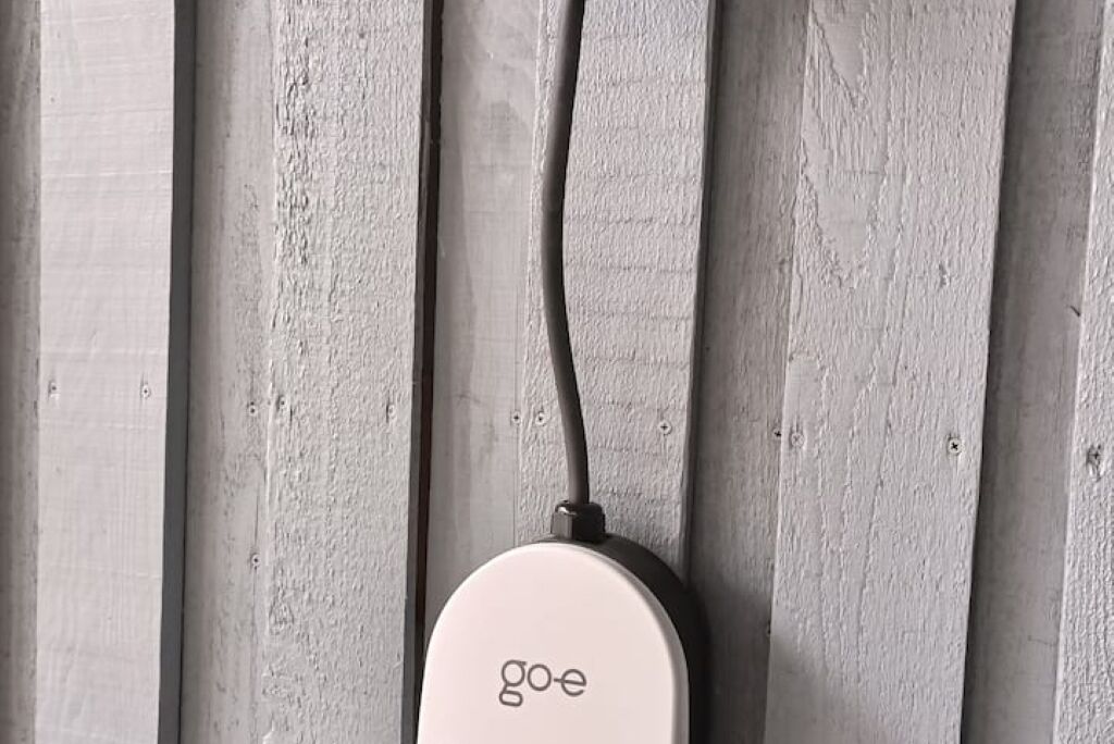 A white Go-E device mounted on a wooden wall.